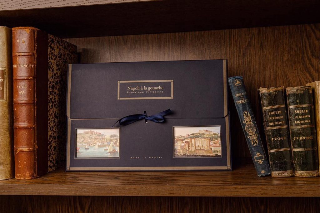 Calendario chiuso Napoli à la gouache di Edizioni Savarese, blu e oro, tra libri antichi